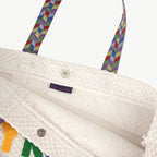 Close-up of a white textured bag with colorful handles and a visible brand label.